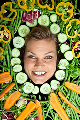 Image showing Cute blond girl shot in studio with vegetables aroound the head