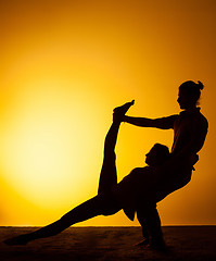 Image showing Two people practicing yoga in the sunset light