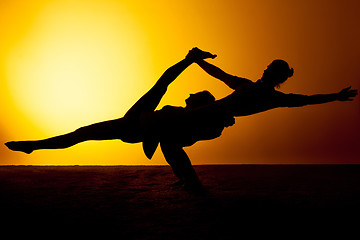 Image showing Two people practicing yoga in the sunset light