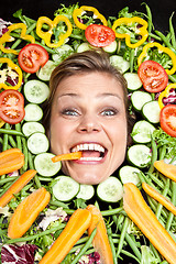 Image showing Cute blond girl shot in studio with vegetables aroound the head