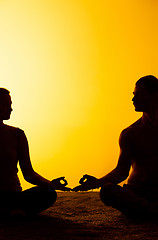 Image showing Two people practicing yoga in the sunset light