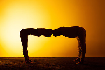 Image showing Two people practicing yoga in the sunset light