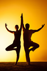 Image showing Two people practicing yoga in the sunset light