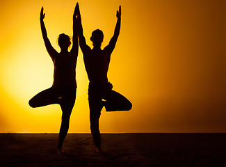 Image showing Two people practicing yoga in the sunset light