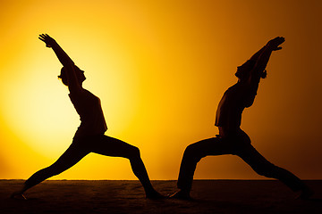 Image showing Two people practicing yoga in the sunset light