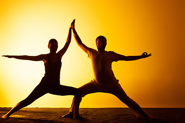 Image showing Two people practicing yoga in the sunset light