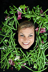 Image showing Cute blond girl shot in studio with vegetables aroound the head