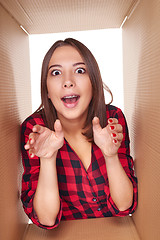 Image showing Girl opening a carton box and looking inside