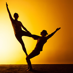 Image showing Two people practicing yoga in the sunset light