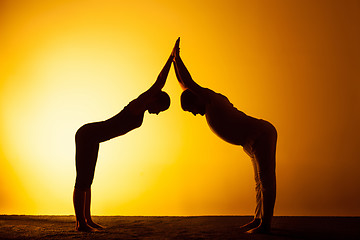 Image showing Two people practicing yoga in the sunset light