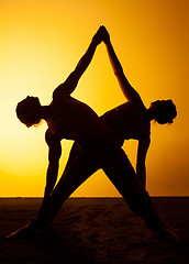 Image showing Two people practicing yoga in the sunset light