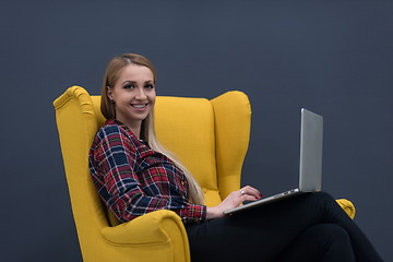 Image showing startup business, woman  working on laptop and sitting on yellow