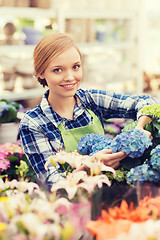 Image showing happy woman taking care of flowers in greenhouse