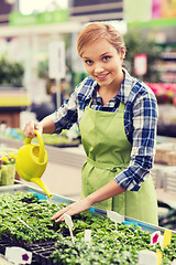 Image showing happy woman with watering can in greenhouse