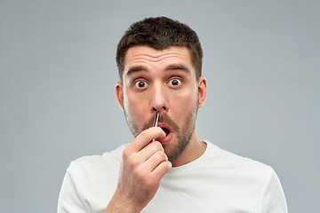 Image showing man with tweezers tweezing hair from nose