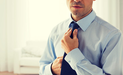 Image showing close up of man in shirt adjusting tie on neck