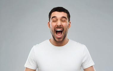 Image showing crazy shouting man in t-shirt over gray background