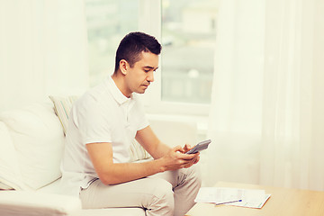 Image showing man with papers and calculator at home