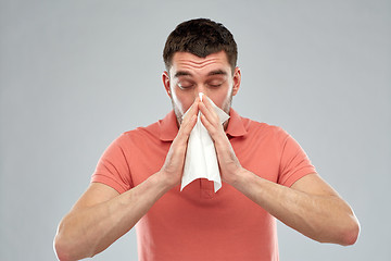 Image showing sick man with paper napkin blowing nose