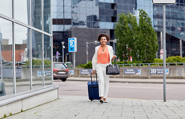 Image showing happy young african woman with travel bag in city