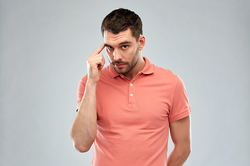 Image showing man with finger at temple over gray background