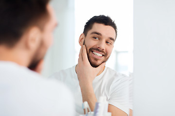 Image showing happy young man looking to mirror at home bathroom