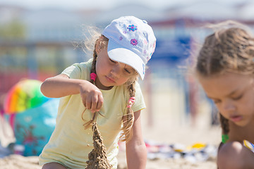 Image showing Four-year girl builds a sand castle on the beach