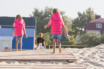 Image showing Two daughters go home for his mother on the wooden flooring in the sand