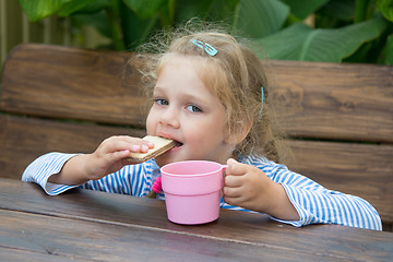 Image showing Four-year girl waffle bites and drinks tea