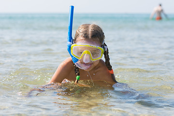 Image showing The girl emerged from the water with a mask on his face and respiratory tube smiling and looking into the frame