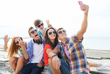 Image showing happy friends with smartphone taking selfie