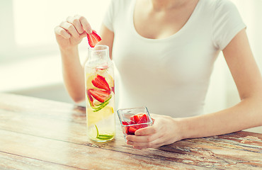 Image showing close up of woman with fruit water in glass bottle