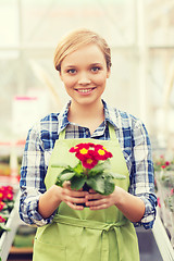 Image showing happy woman holding flowers in greenhouse