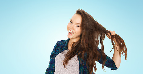 Image showing happy teenage girl holding strand of her hair