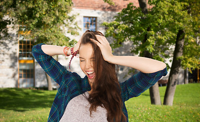 Image showing happy pretty teenage student girl holding to head