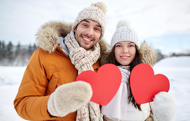 Image showing happy couple with red hearts over winter landscape