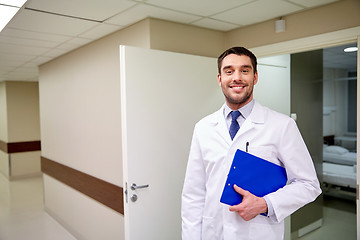 Image showing happy doctor with clipboard at hospital corridor