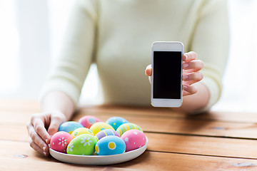 Image showing close up of hands with easter eggs and smartphone