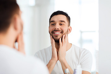 Image showing happy young man looking to mirror at home bathroom