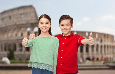 Image showing happy boy and girl showing thumbs up over coliseum