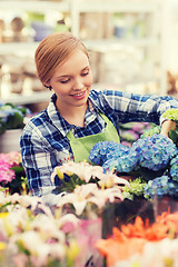 Image showing happy woman taking care of flowers in greenhouse