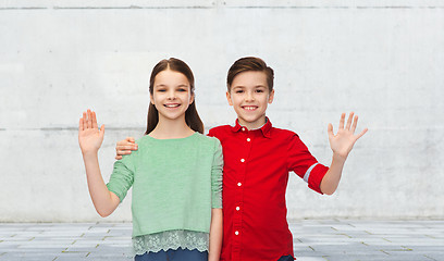 Image showing happy boy and girl waving hand