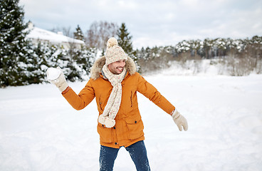 Image showing happy young man playing snowballs in winter