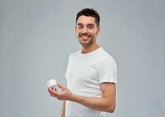 Image showing happy young man with cream jar over gray