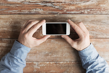 Image showing close up of male hands with smartphone on table