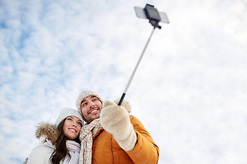 Image showing happy couple taking selfie by smartphone in winter