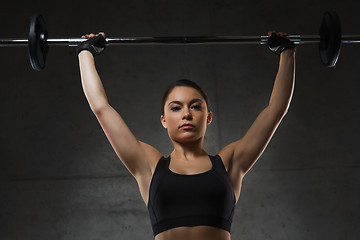 Image showing young woman flexing muscles with barbell in gym