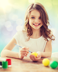 Image showing happy girl with brush coloring easter eggs