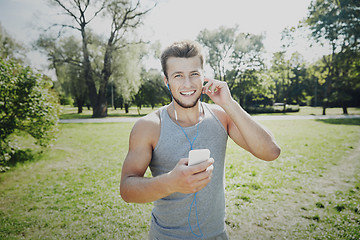 Image showing happy man with earphones and smartphone at park