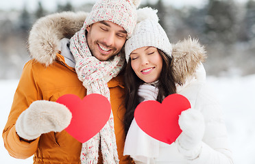 Image showing happy couple with red hearts over winter landscape